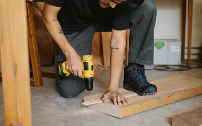 Handyman using a power drill to secure wood, demonstrating carpentry skills for home repairs in Singapore.